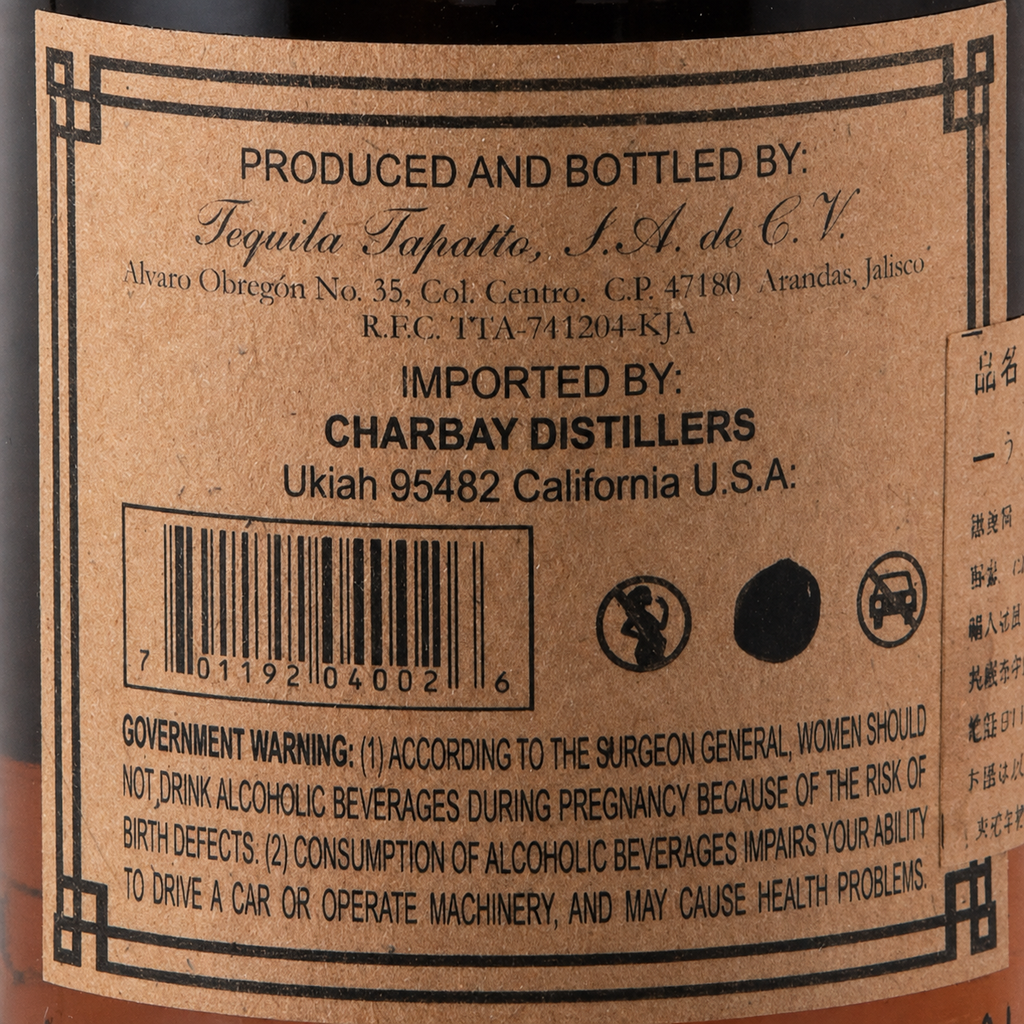 Close-up of a brown paper product label with black text, including 'Produced and Bottled by Tequila Tapatio, S.A.